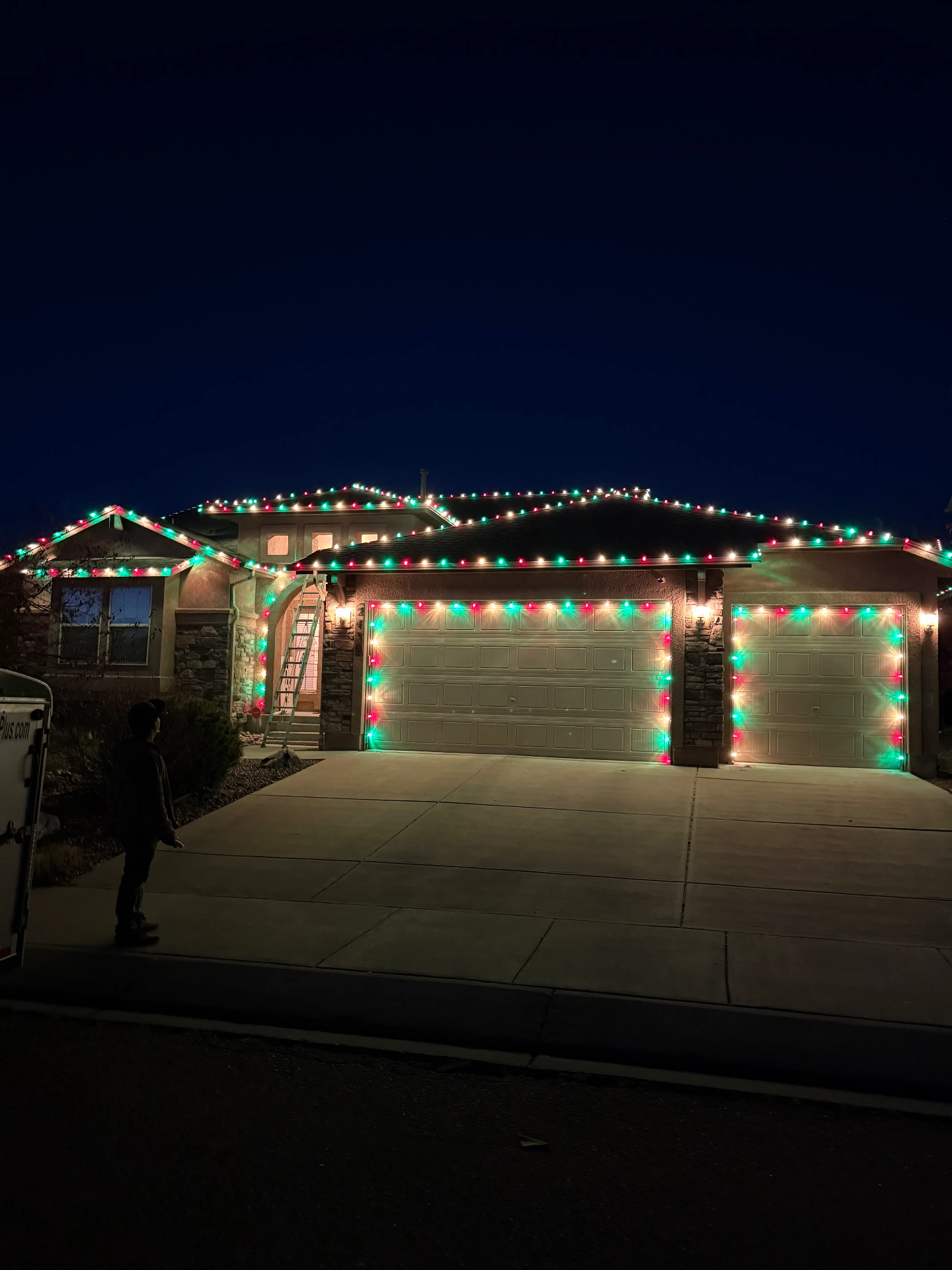 Christmas lights installation Front Range - professional holiday lighting on residential home with red and green LED roofline lights, garage door lighting, and complete outdoor display