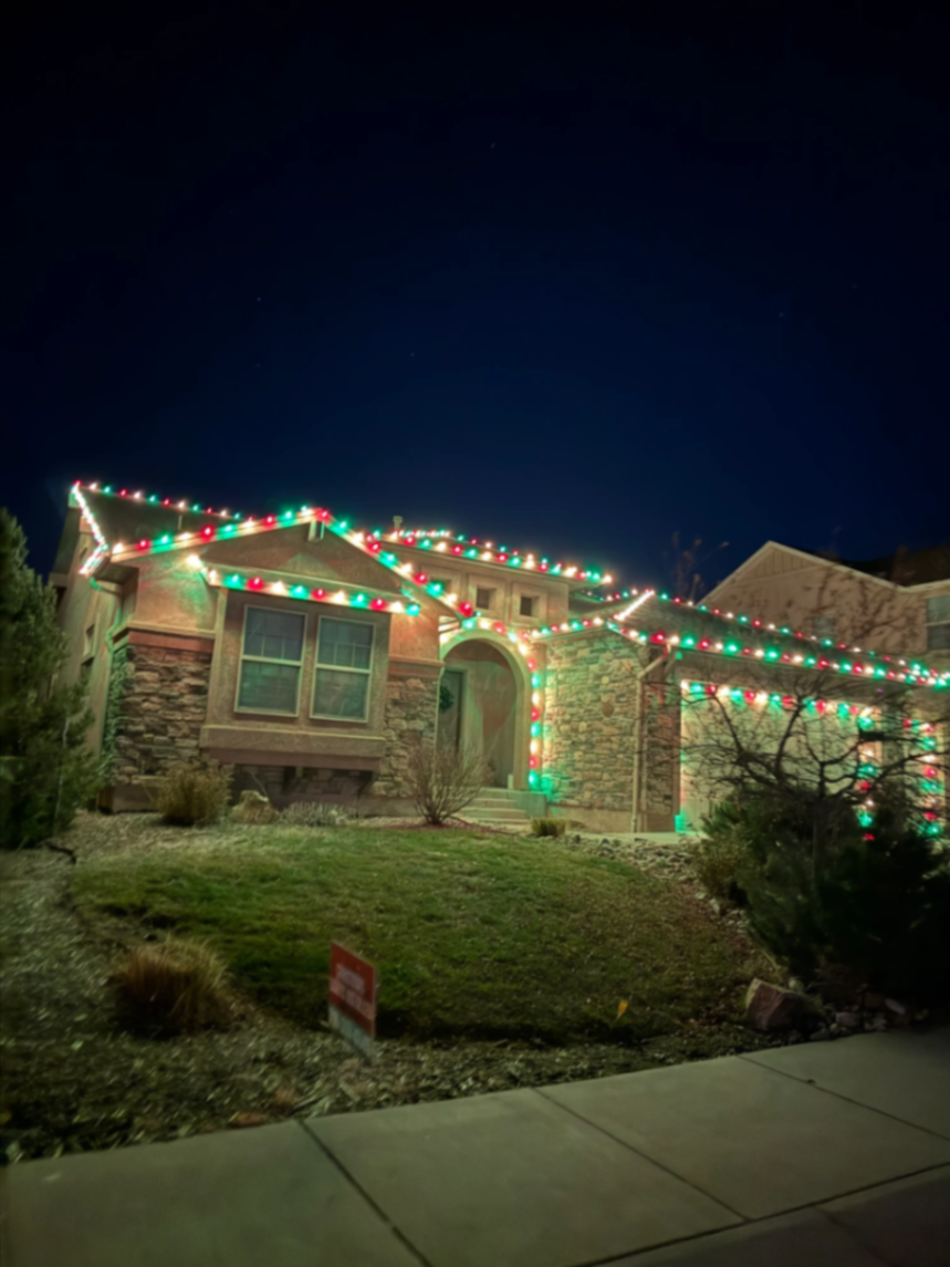 Holiday light installation Front Range CO - stunning Christmas lights on two-story home with multicolor LED bulbs, professional roofline lighting and landscape illumination