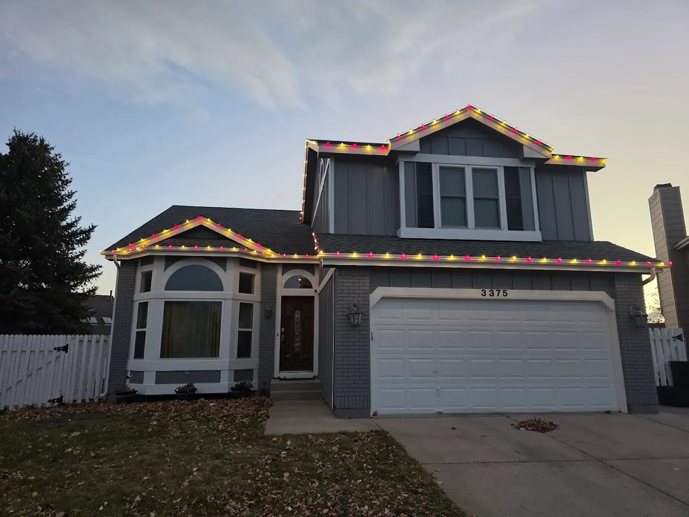 Christmas light installation Front Range two-story home - professional multicolor LED lights featuring red yellow green bulbs on roofline, residential holiday lighting services